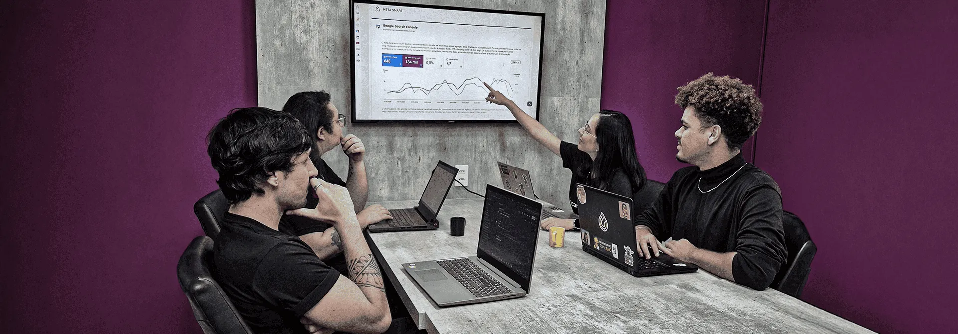 Um homem e uma mulher estão sentados à mesa olhando para um laptop.