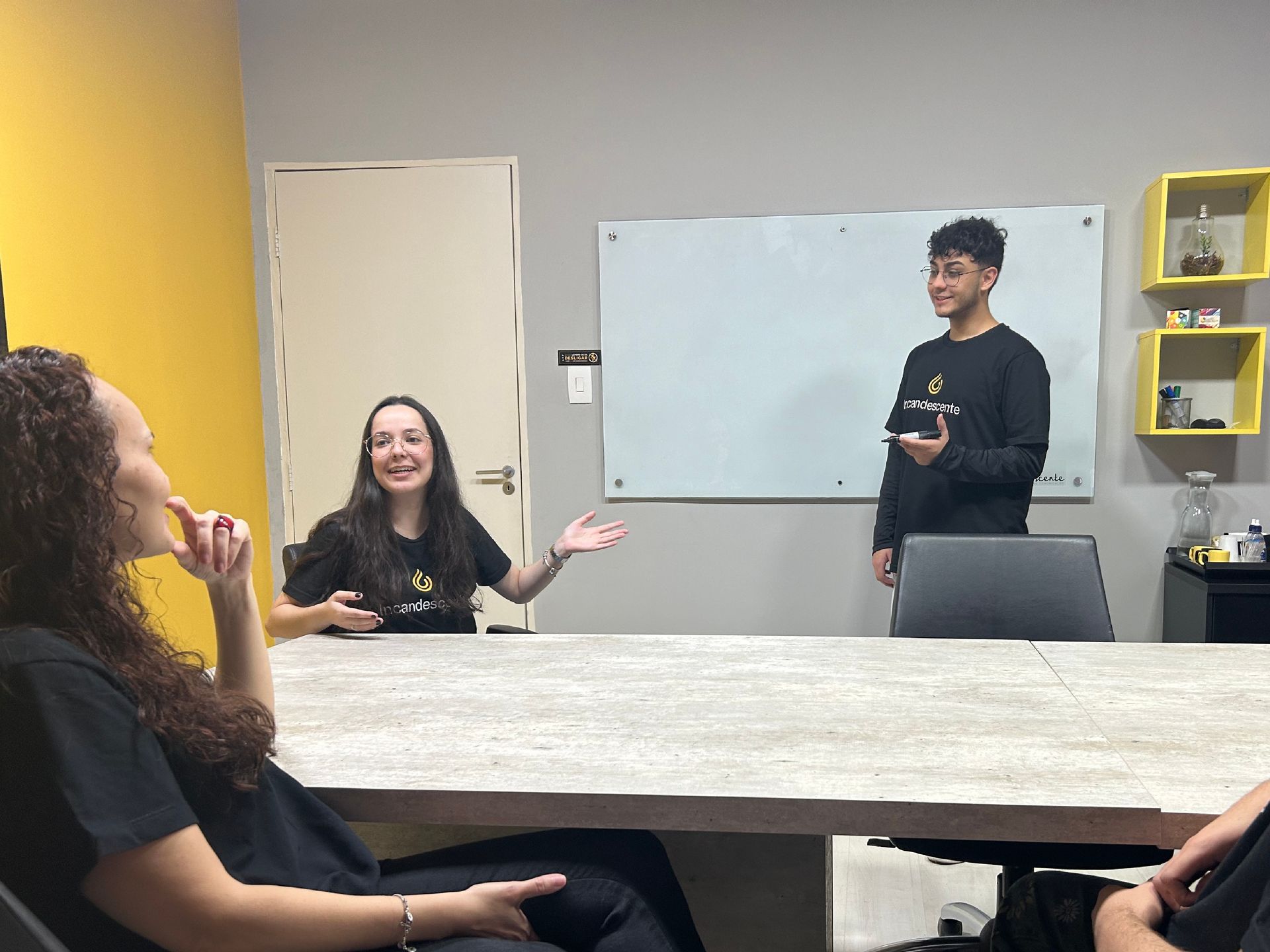Um grupo de pessoas está sentado ao redor de uma mesa em uma sala de conferências.